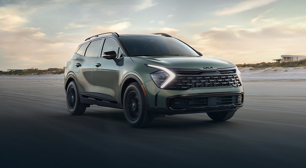 A green 2025 Kia Sportage X-Pro driving off-road on a beach from a dealer with a Kia Sportage for sale near Chicago.