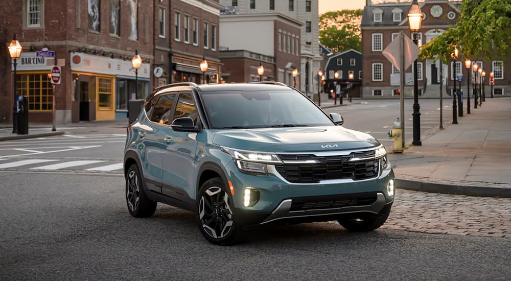 A green 2025 Kia Seltos for sale driving around a corner.