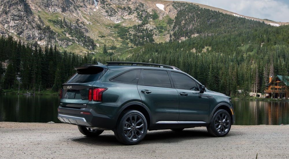 Side angle view of a dark green 2023 Kia Sorento X-Line parked near a lake.