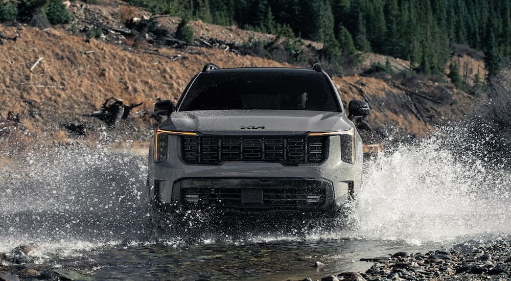 Front of a grey 2026 Kia Sorento X-Pro SX Prestige driving over a shallow pond.