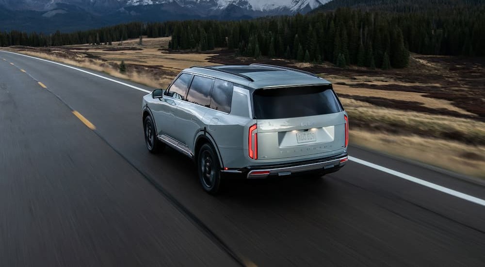 A silver 2027 Kia Telluride driving to a Kia dealer near Bartlett.