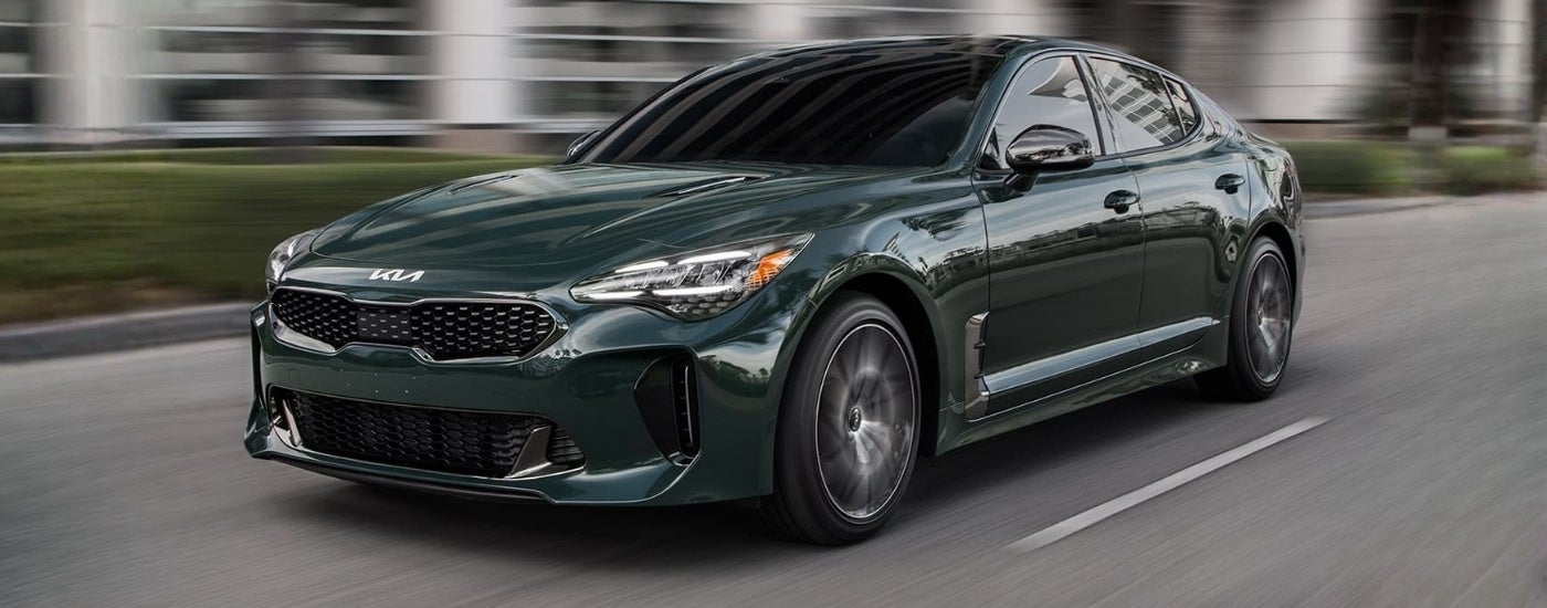 Green 2023 Kia Stinger driving on a city sreet