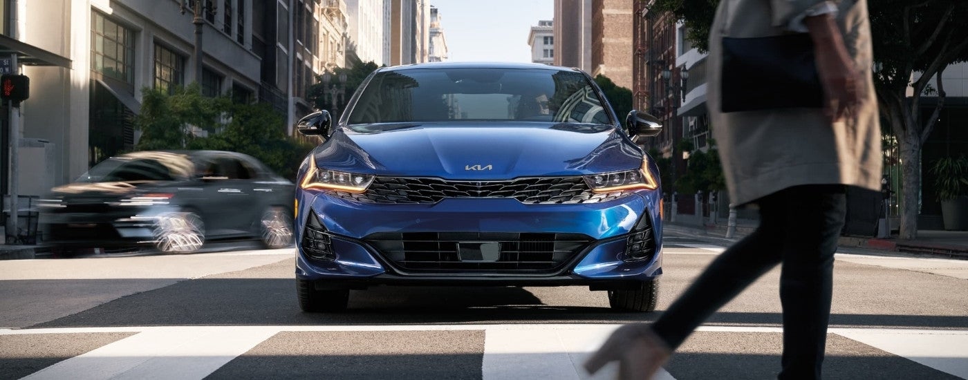 Blue 2024 Kia K5 driving over a crosswalk