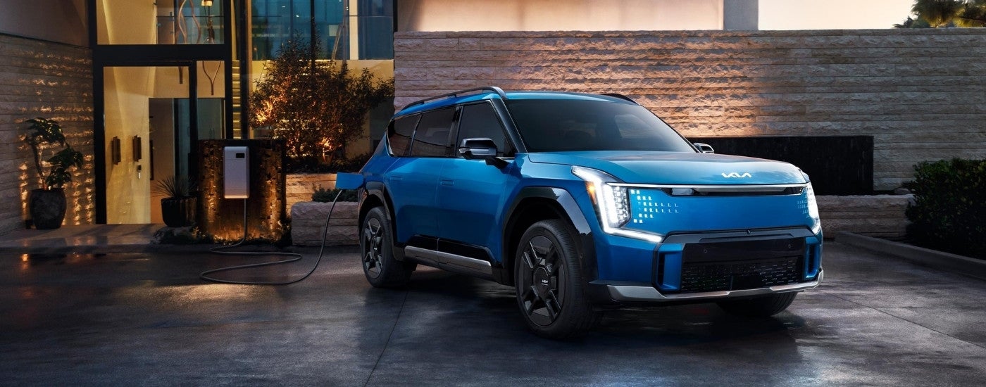 Blue 2025 Kia EV9 charging on a driveway