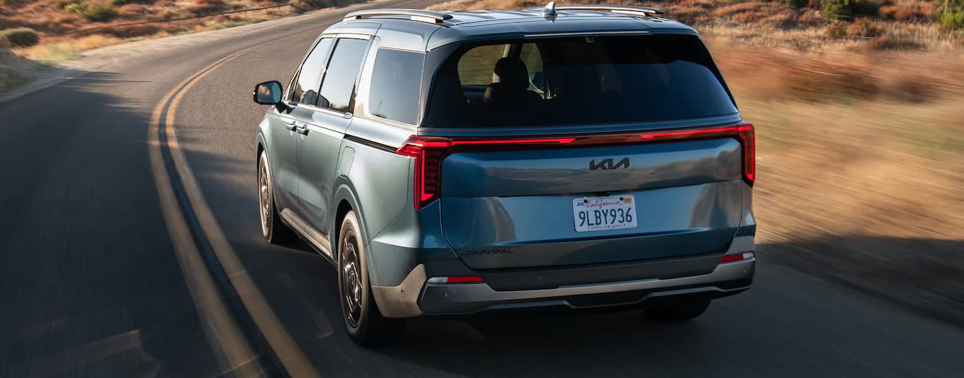 Rear of a blue 2026 Kia Carnival driving