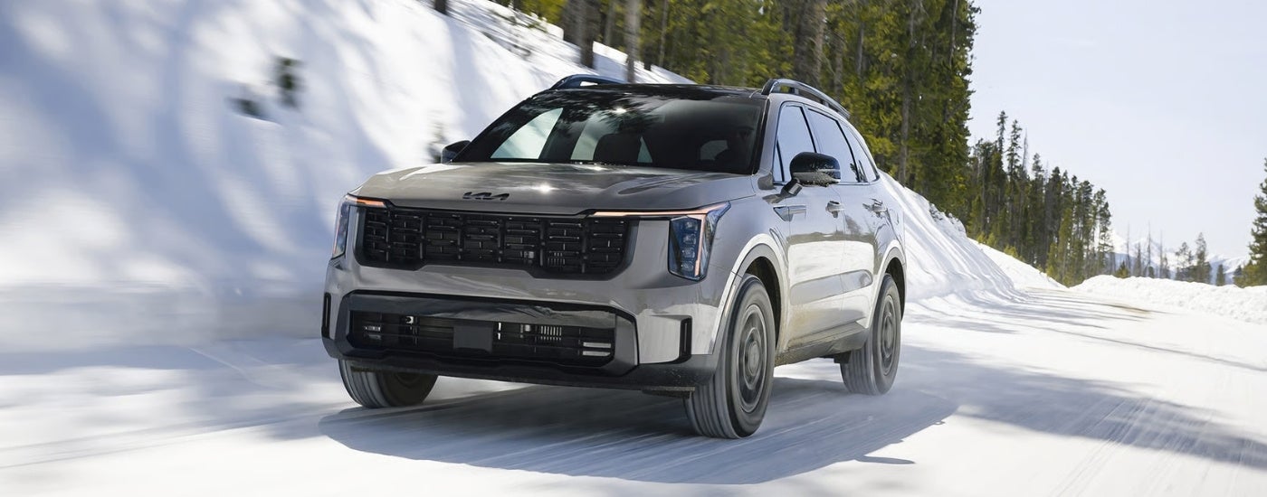 Grey 2026 Kia Sorento X-Pro SX Prestige driving past a snow covered hill