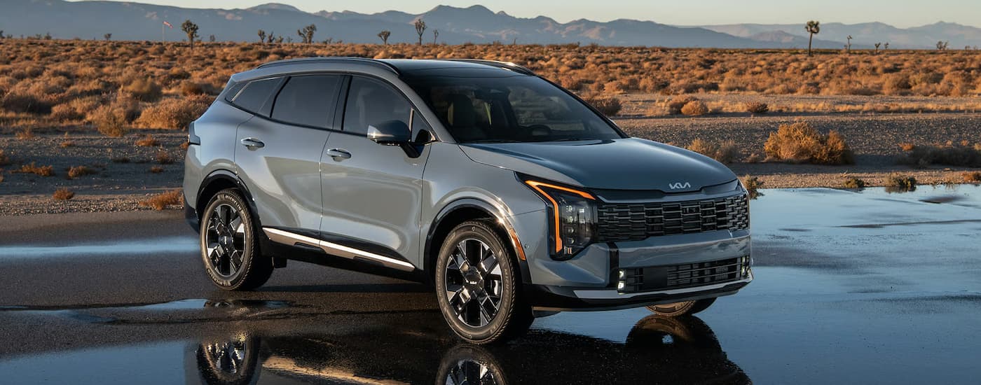 Grey 2026 Kia Sportage parked in an open lot near the desert