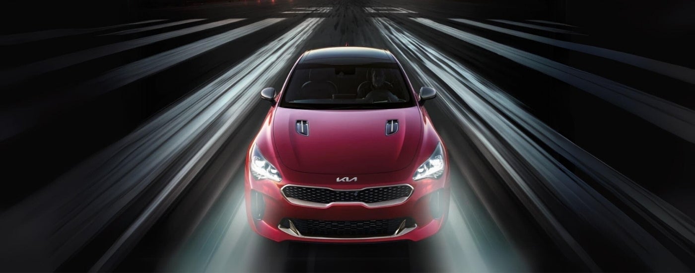 A red 2021 Kia Stinger is shown from the front driving on an airstrip.