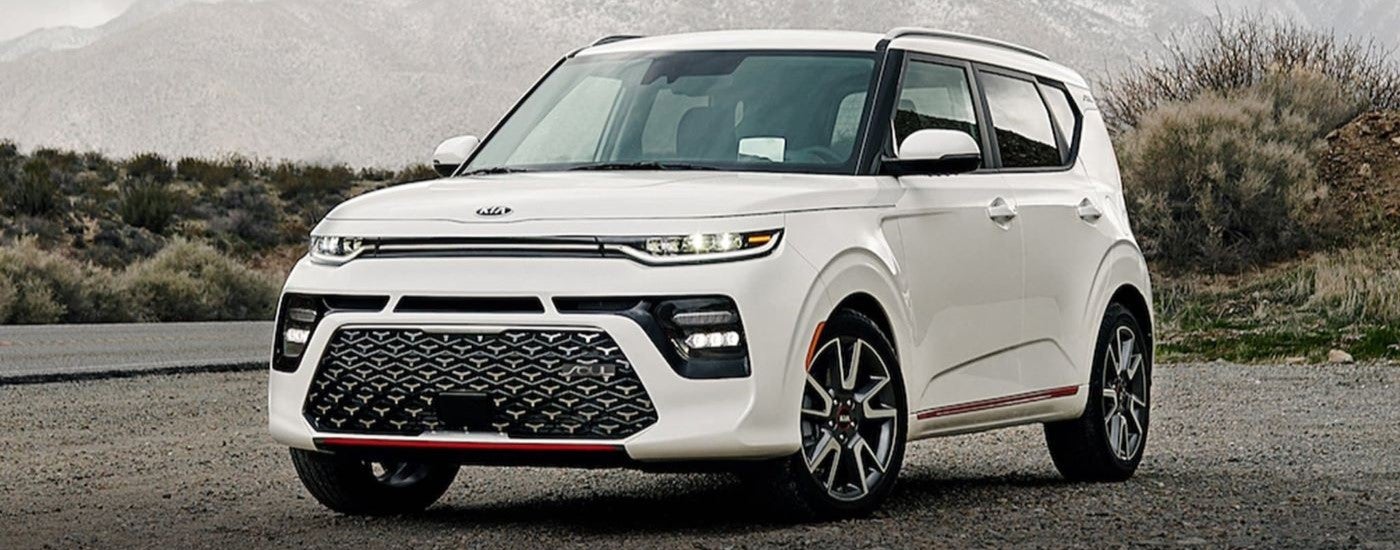 A white 2021 Kia Soul angled left and driving from a Kia dealer near Mount Prospect.