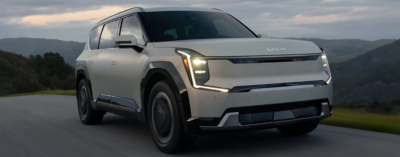 A silver 2024 Kia EV9 driving to a Kia dealer near Skokie.