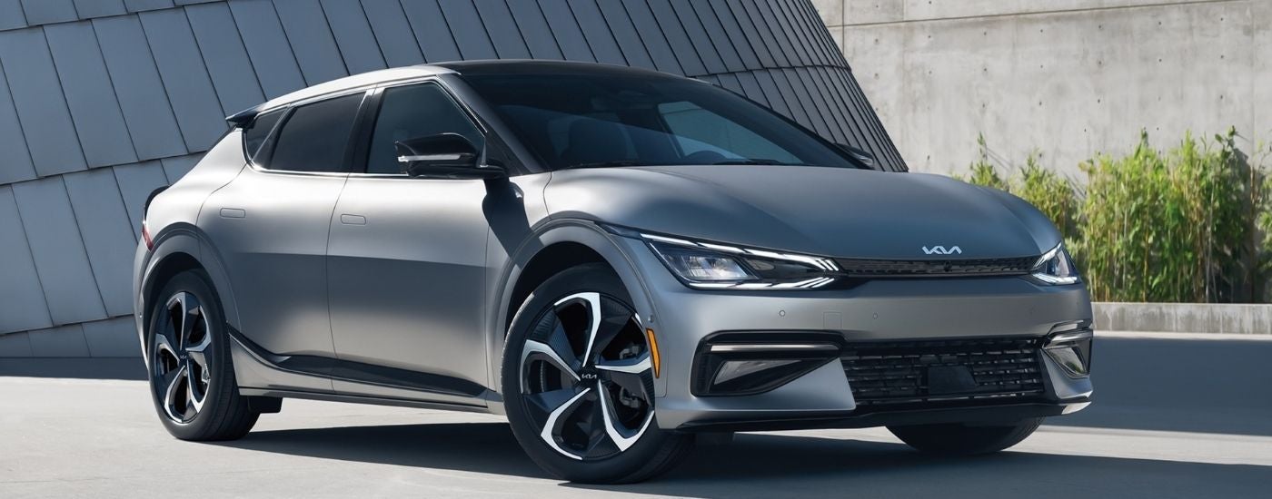 A silver 2024 Kia EV6 parked outside a modern building.