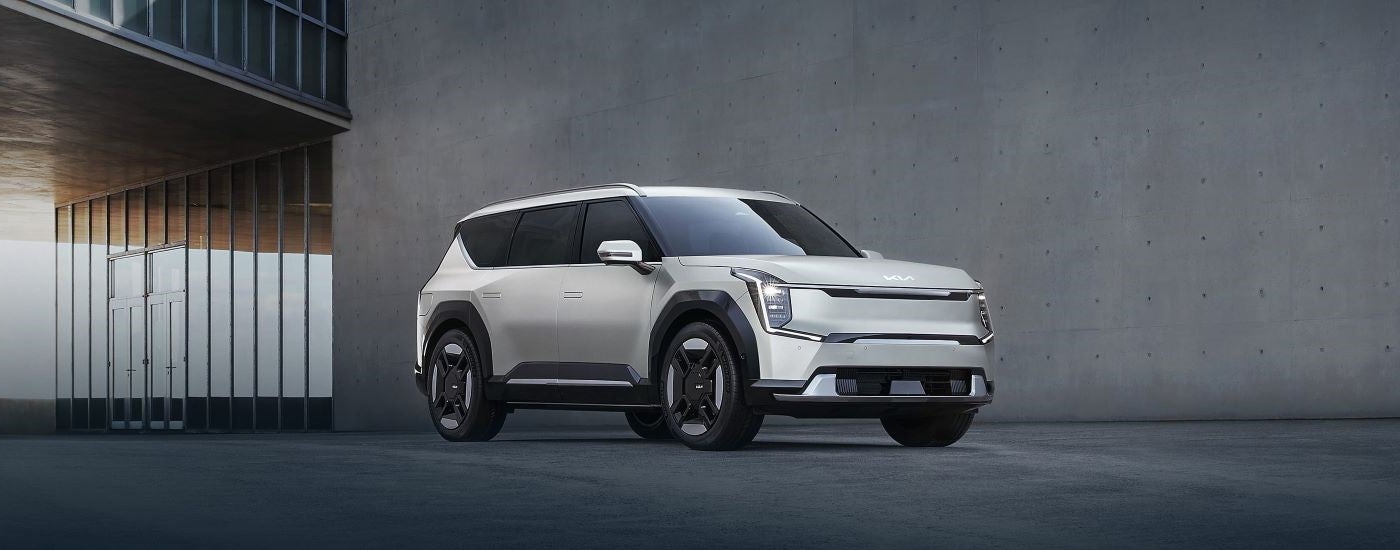 A white 2024 Kia EV9 parked outside a building and angled right.