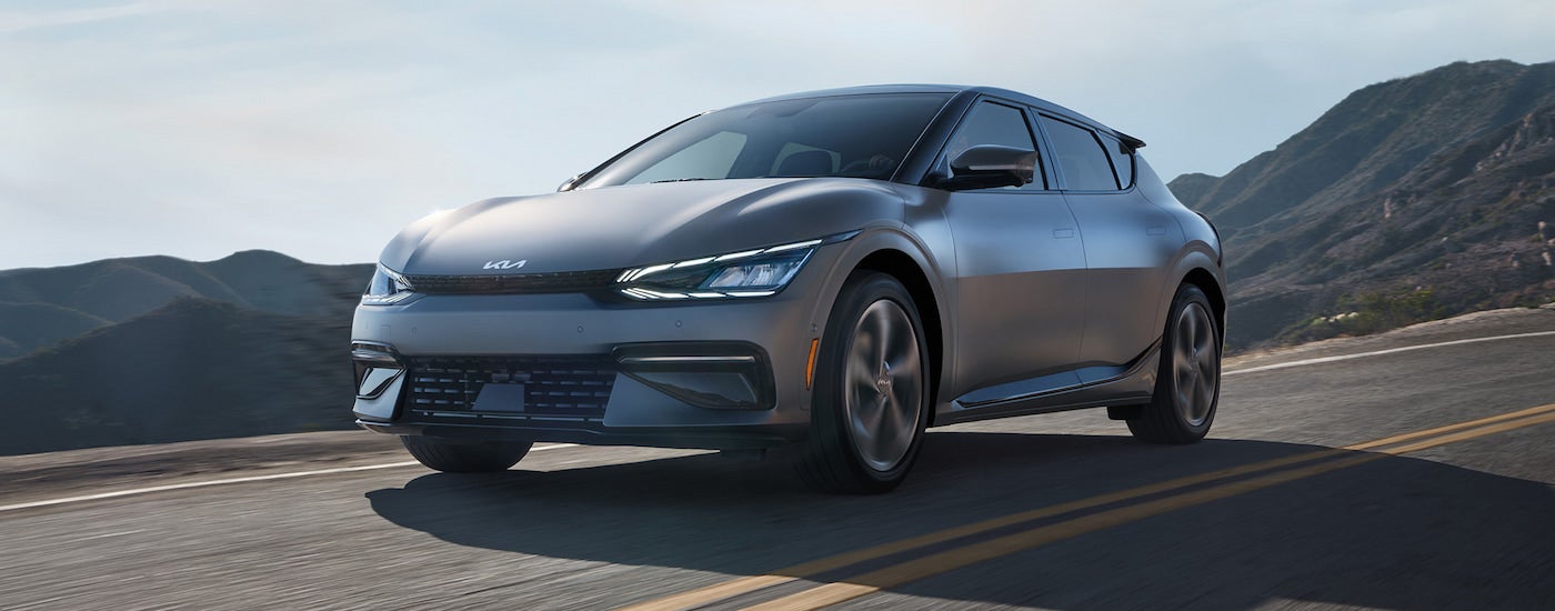 A silver 2024 Kia EV6, a Kia for sale, driving on an open road.