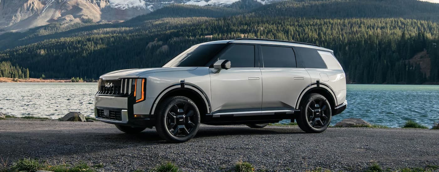 Silver 2026 Kia Telluride parked off-road near a lake.