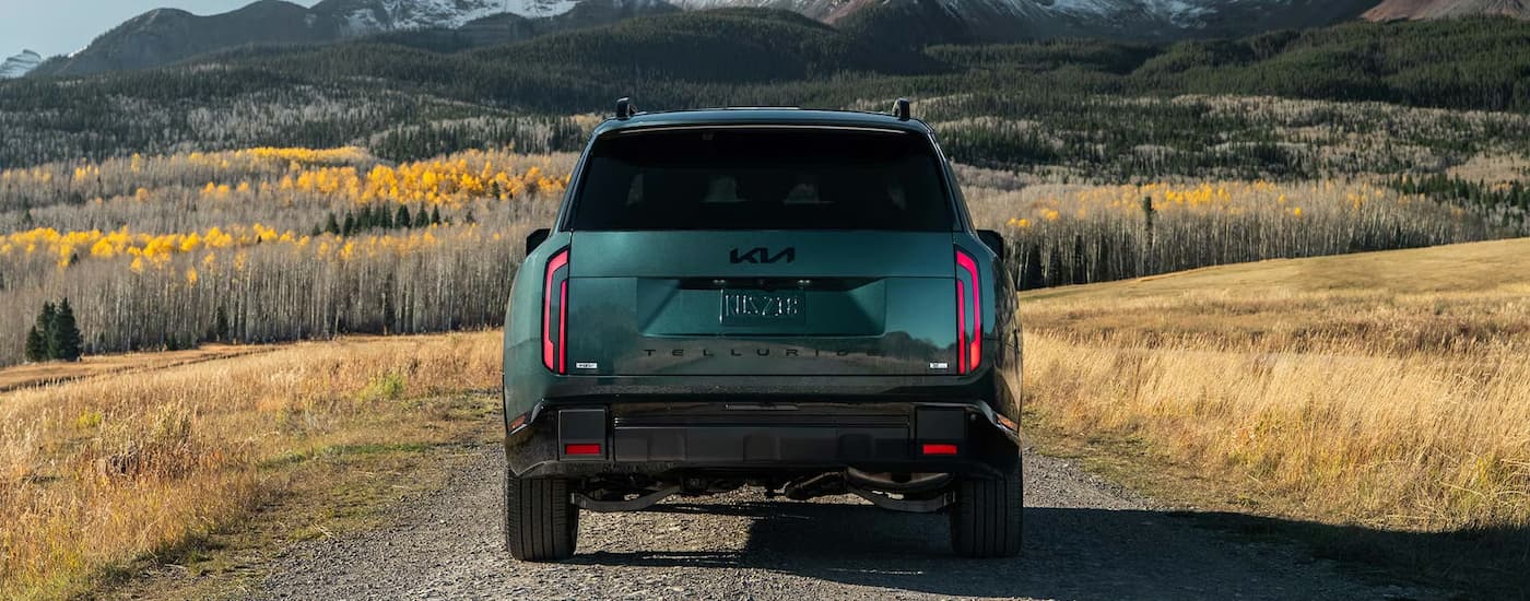 Rear of a dark green 2026 Kia Telluride driving on a trail.