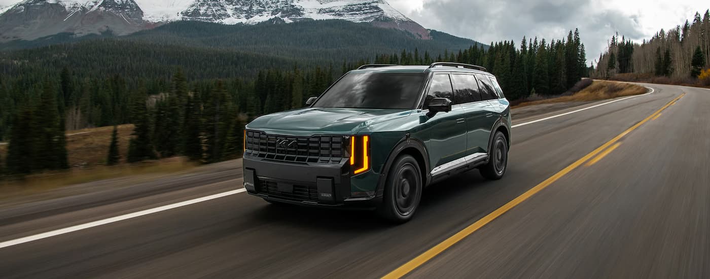 Dark green 2026 Kia Telluride driving around a bend.