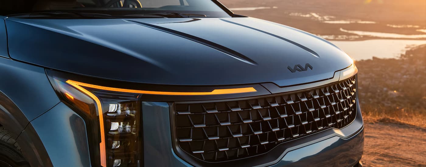 Front grille of a blue 2026 Kia Carnival MPV